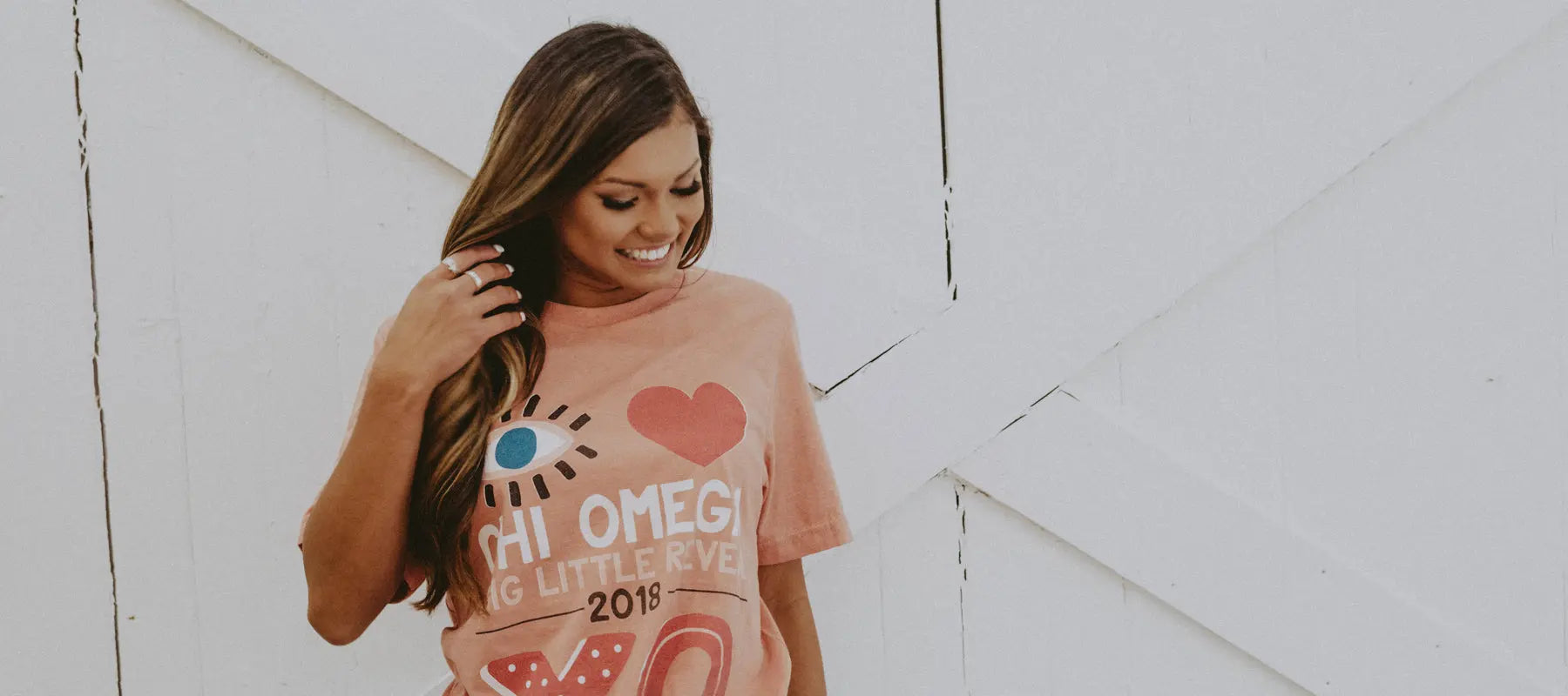 Girl wears an orange tshirt that reads, "I love Chi Omega"
