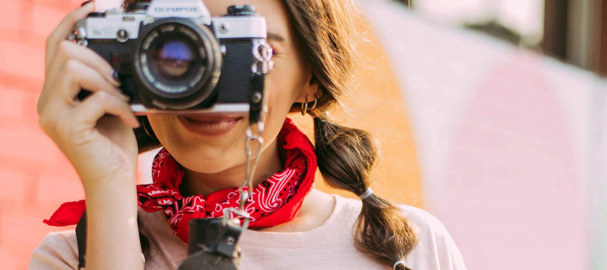 Girl holds a camera and wears a red bandana around her neck