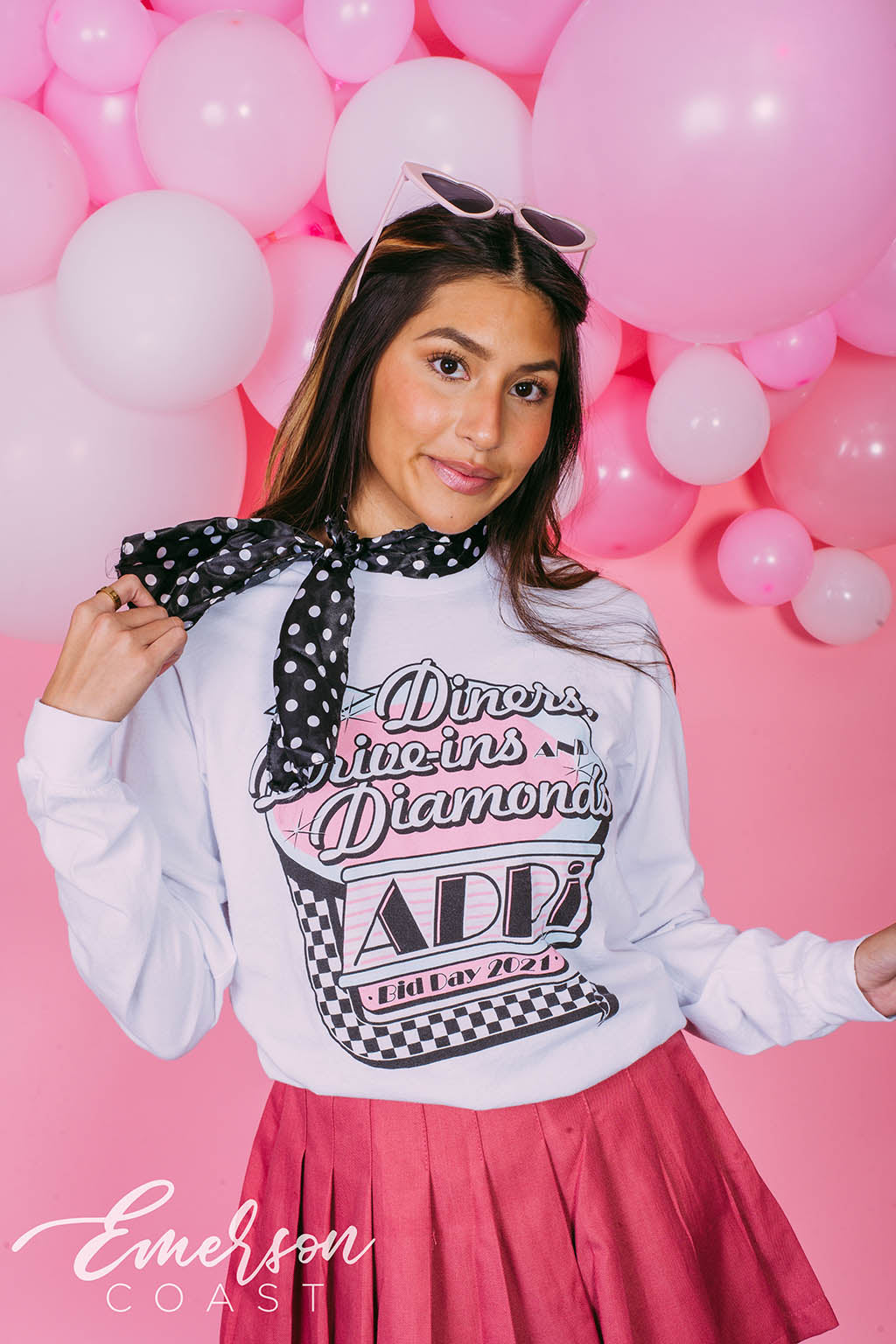 Girl wears white long sleeve that reads "Diners, Drive-ins, and Diamonds. ADPi Bid Day."