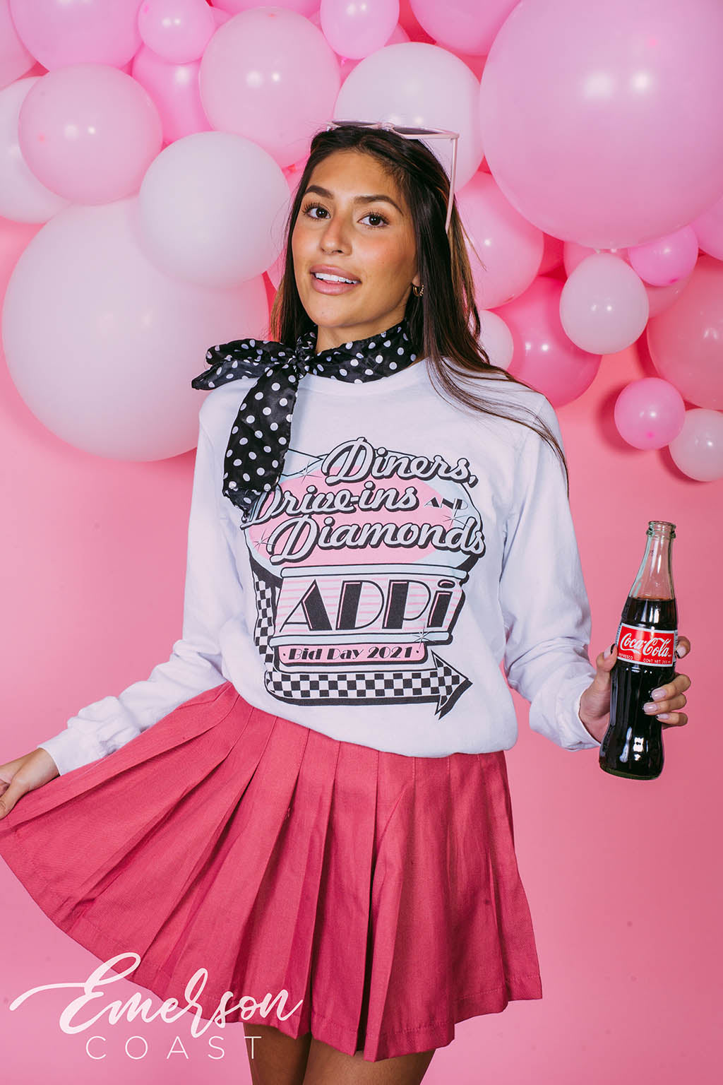 Girl wears white long sleeve that reads "Diners, Drive-ins, and Diamonds. ADPi Bid Day."