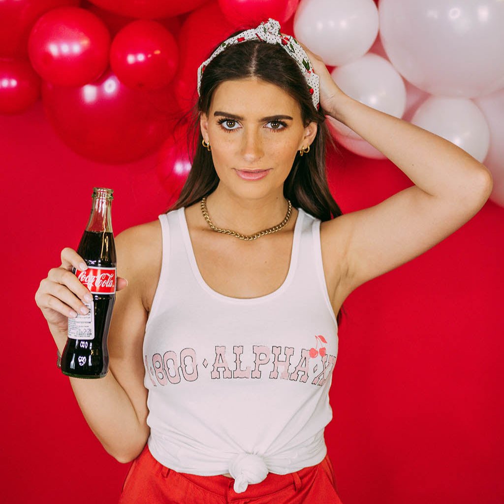 Girl wears white tank with 1-800-Alpha-Xi written across it.