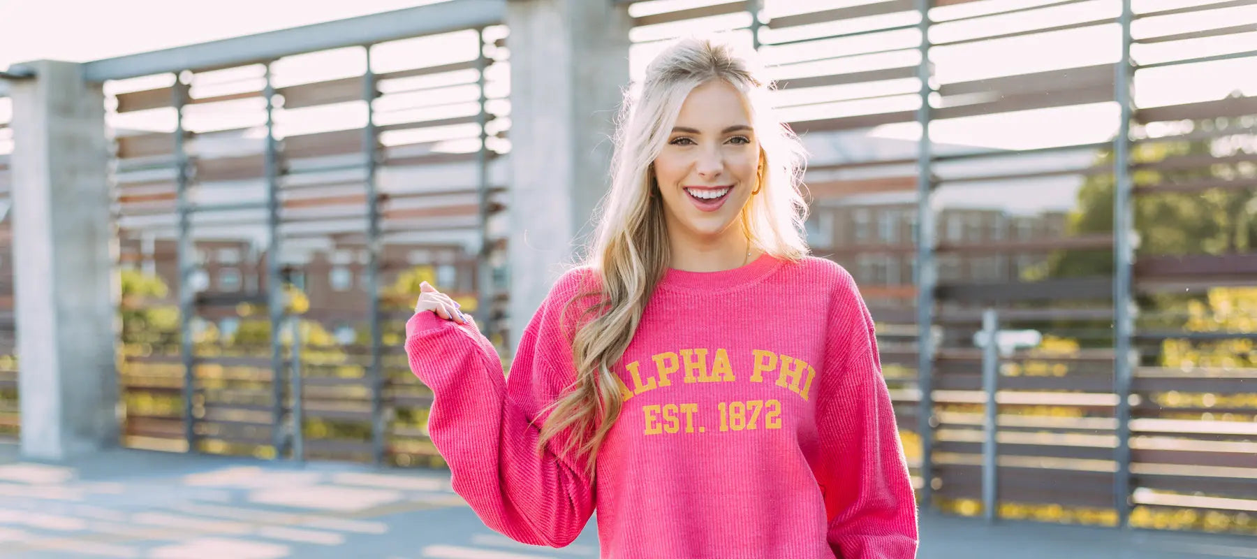 Girl wears a pink Alpha Phi corduroy sweatshirt