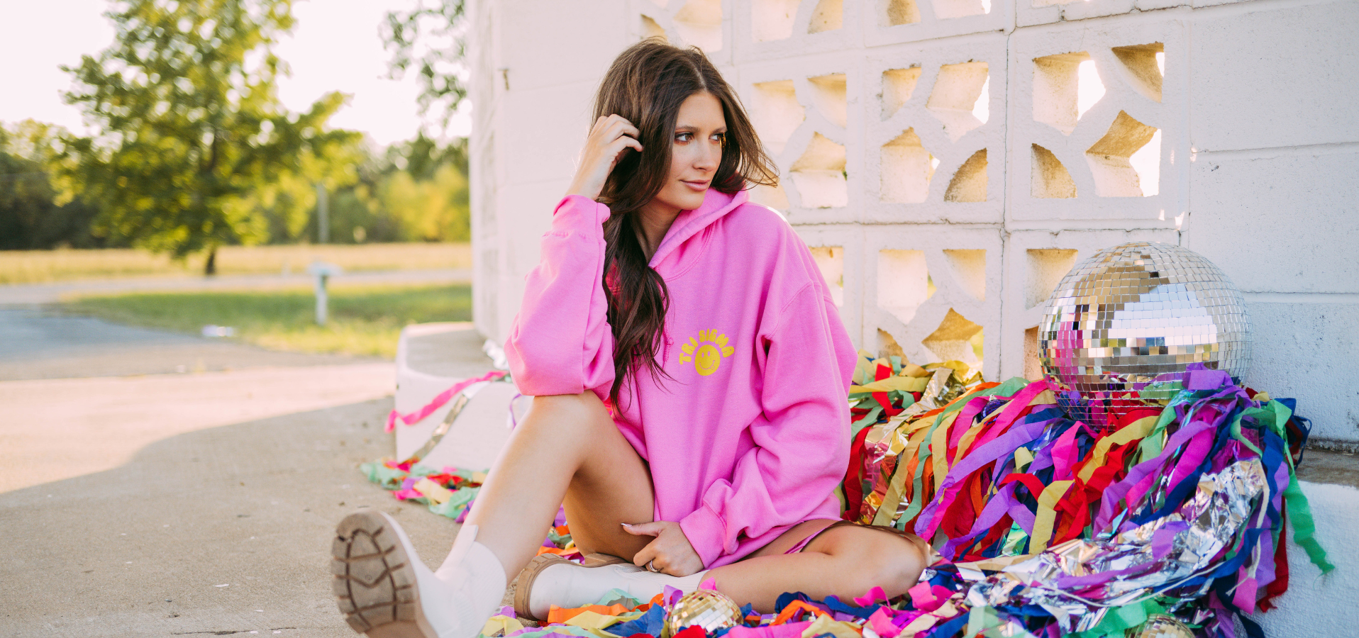 Girl wears a pink hoodie with Tri Sigma and a smiley face on the left chest.