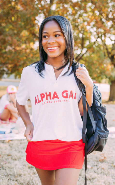Girl wears a white tshirt that reads Alpha Gam