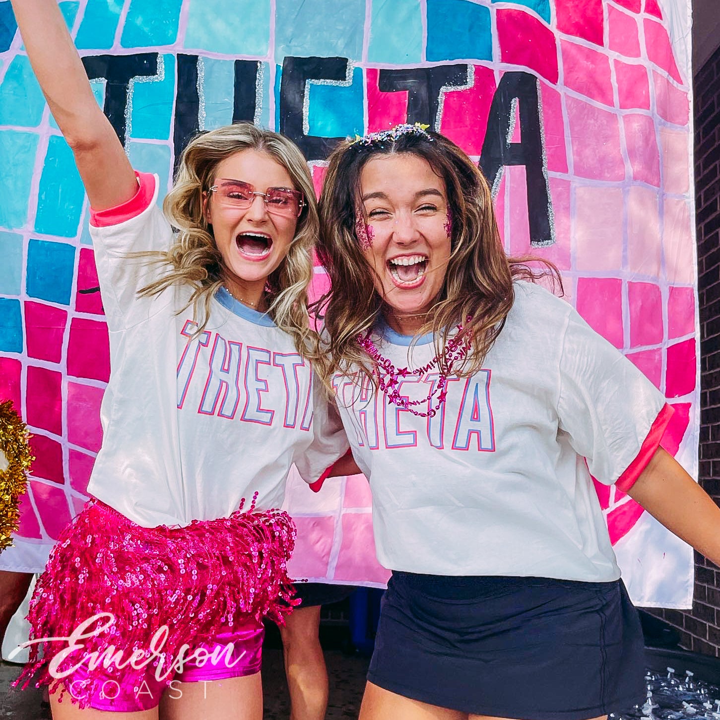 picture is of 2 girls wearing white ringer tshirts that say Theta in pink and blue font