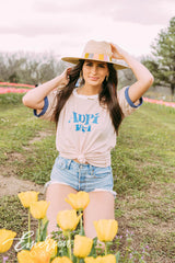 Girl sits in tulip field wearing a white ADPi 1851 ringer tshirt.