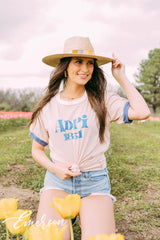 Girl sits in tulip field wearing a white ADPi 1851 ringer tshirt.