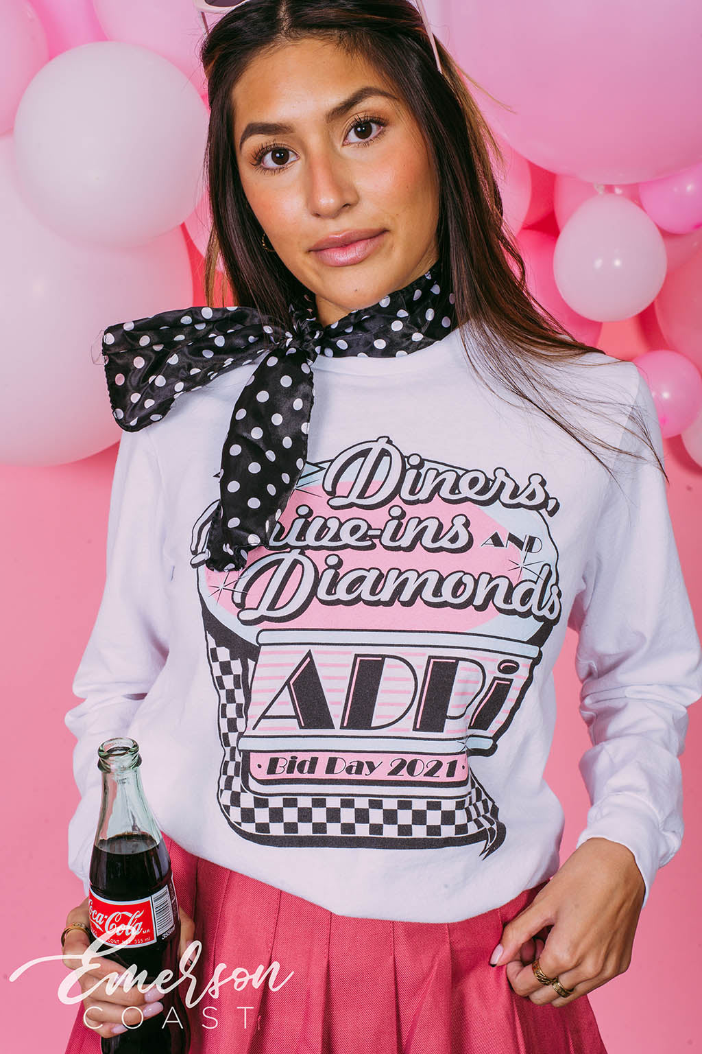 Girl wears white long sleeve that reads &quot;Diners, Drive-ins, and Diamonds. ADPi Bid Day.&quot;