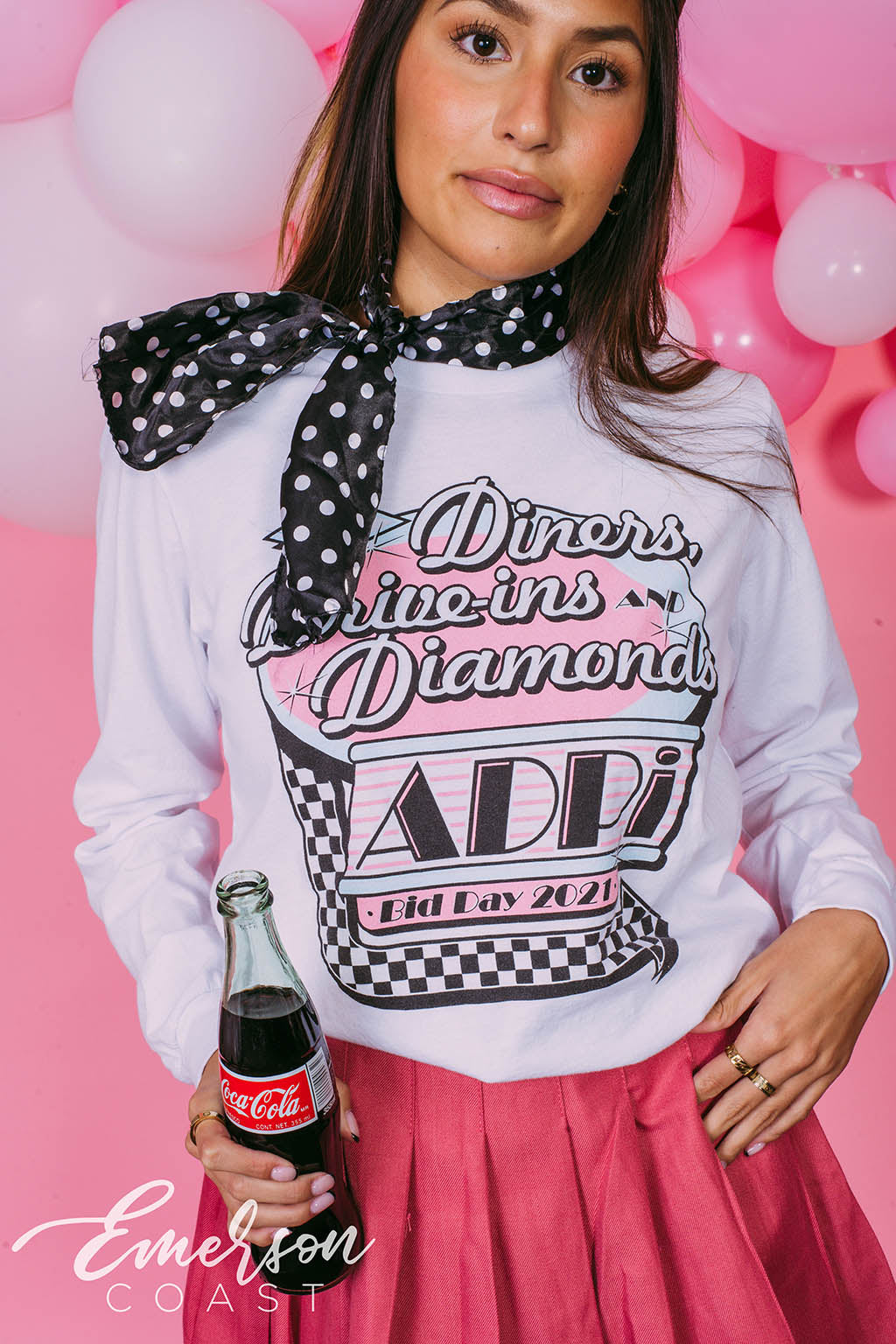 Girl wears white long sleeve that reads "Diners, Drive-ins, and Diamonds. ADPi Bid Day."