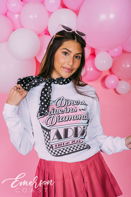 Girl wears white long sleeve that reads "Diners, Drive-ins, and Diamonds. ADPi Bid Day."