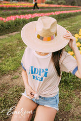Girl sits in tulip field wearing a white ADPi 1851 ringer tshirt.